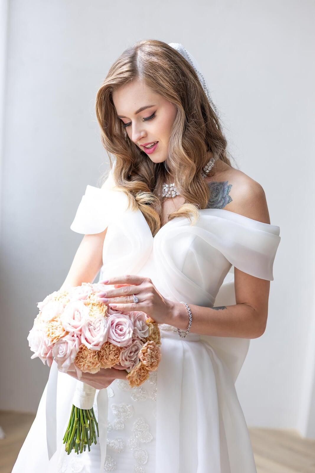 Soft glam bridal makeup look by Makeup by Anu with bride holding pastel wedding bouquet.